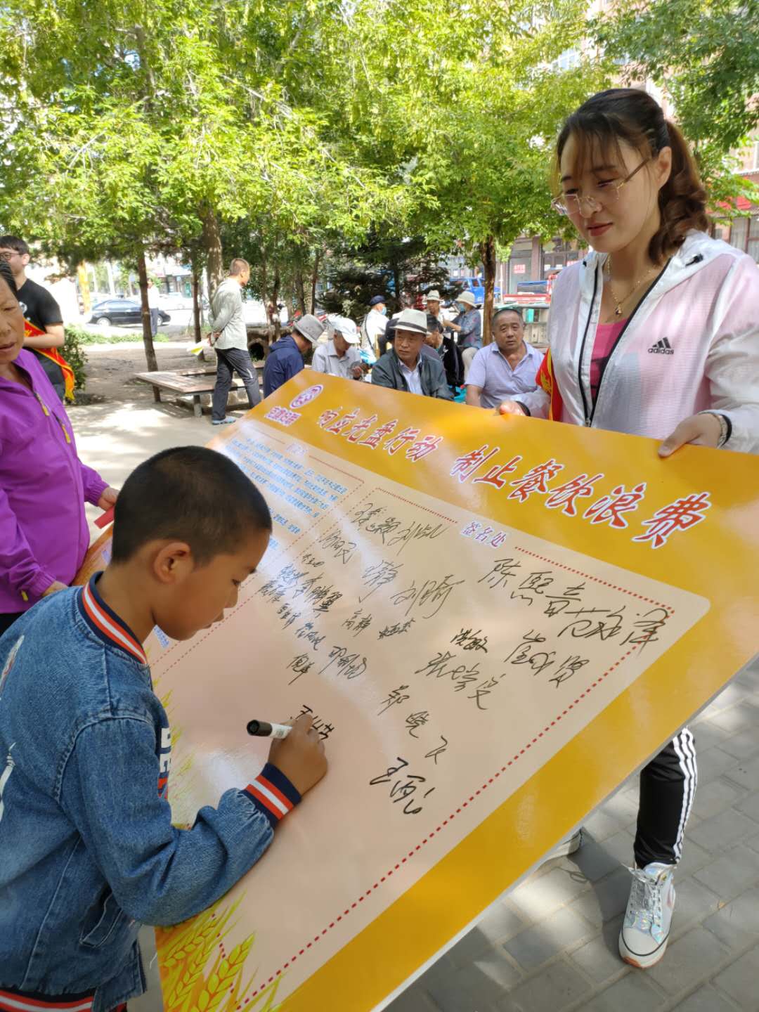 小学生朋友在倡议书宣传板上签字.jpg